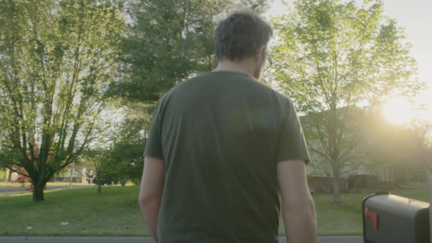 A man walks through his yard to check the mail
