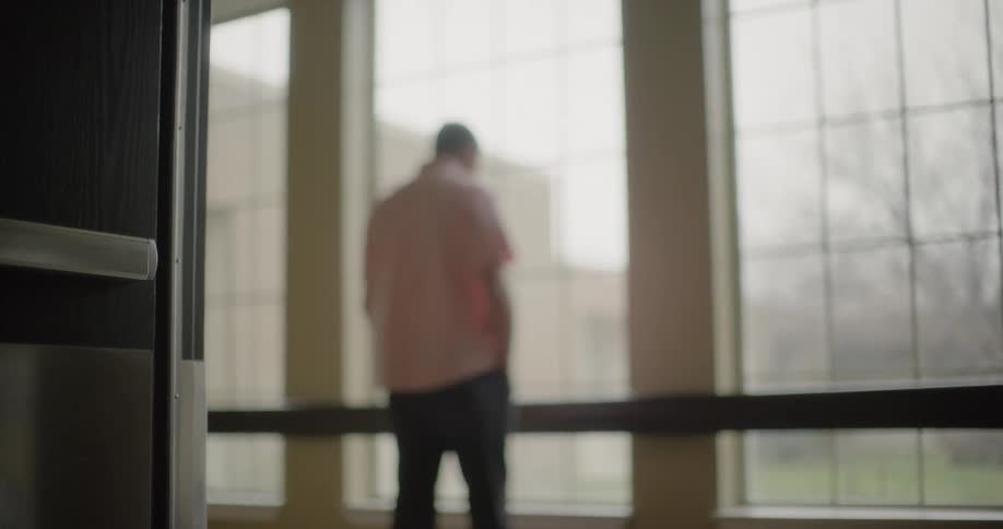 A depressed man leaning against a handrail in a hallway