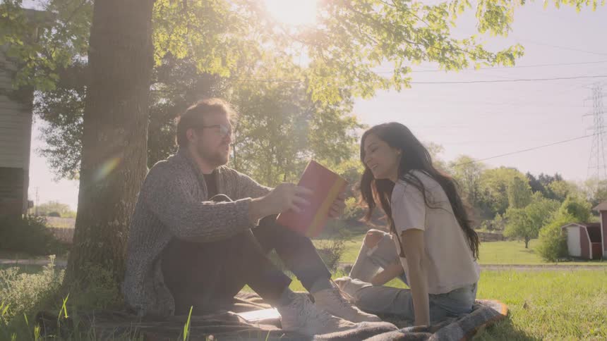 A man and woman sit together with a book