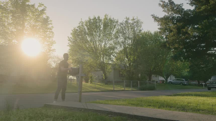 Man picks up the mail from the mail post outdoors at sunrise