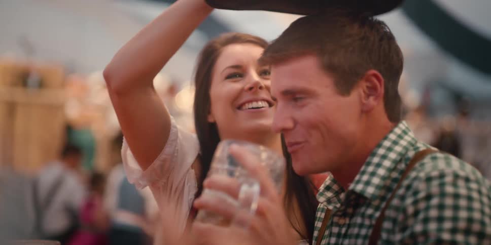 A man and a woman smile and laugh while drinking at an event