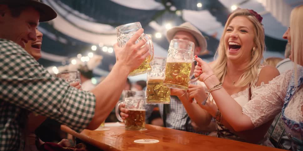 A group of friends dressed in german attire toast mugs of beer