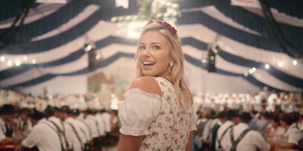 A woman walking in a large gathering with men wearing lederhosen