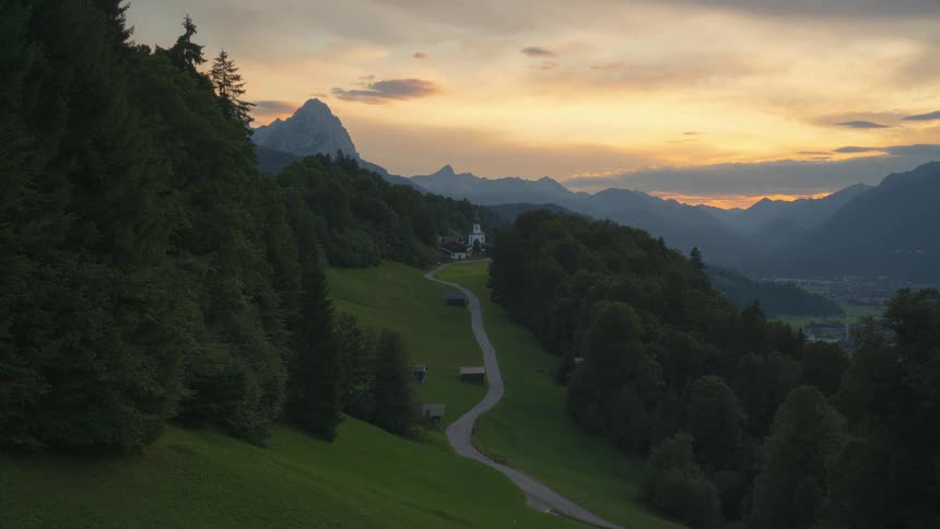 Sun rises over building on mountain and town in valley