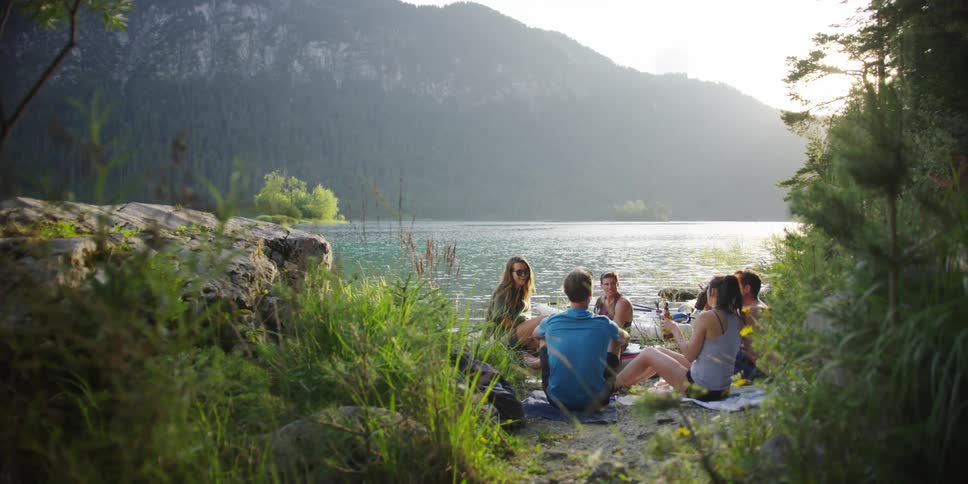 People hang out and drink next to a lake