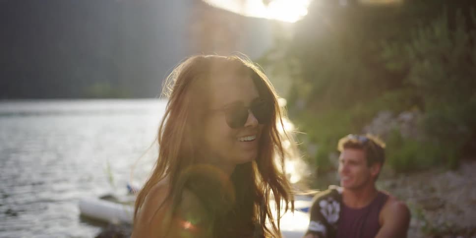 Young couple sitting in a lake shore in the mountains at sunrise