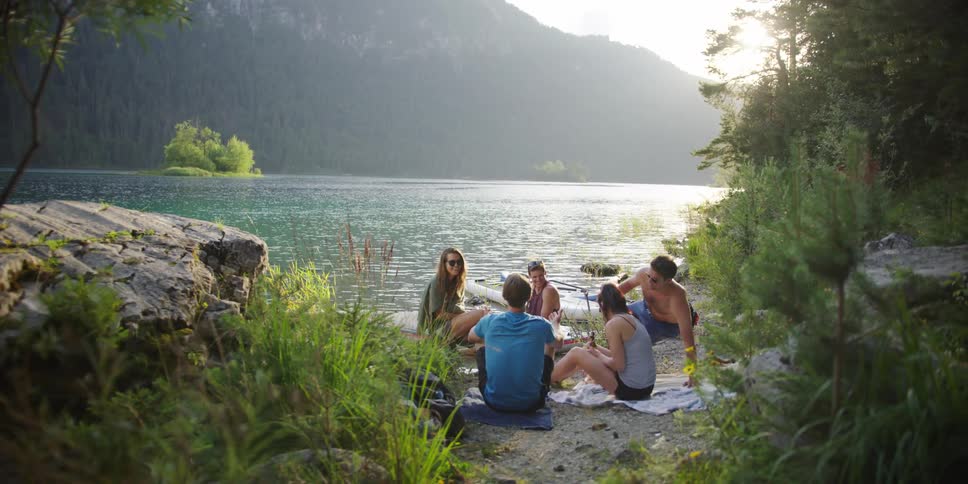 A group of people sitting together on the shore of a lake