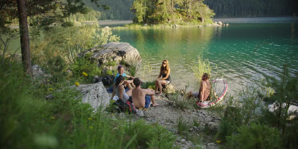 A group of friends sit on the shore and talk
