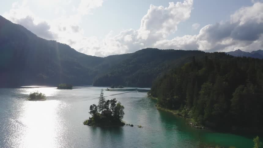 A lake next to a forest with mountains in the background