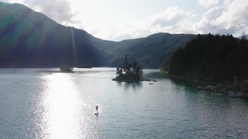 Man sails in kayak on a lake surrounded by mountains at day
