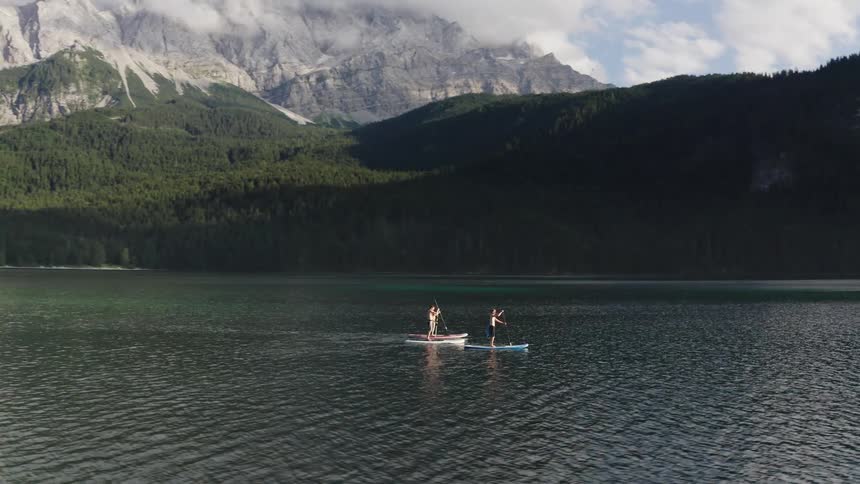 Three people row on surfboards in the lake