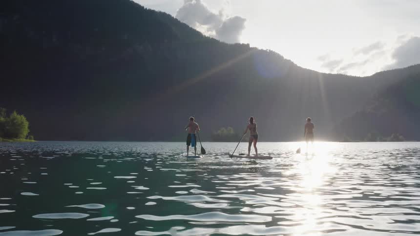 Friends paddleboarding on a lake on sunny day