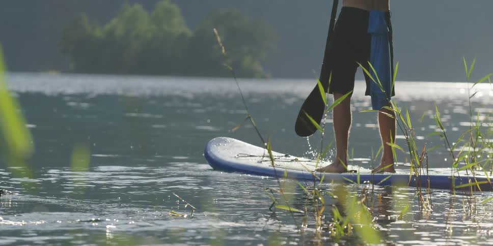 A male paddle boards on a lake