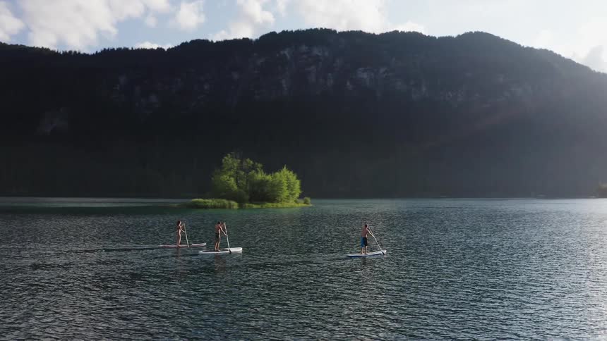 Stand up paddle boarders go across a lake