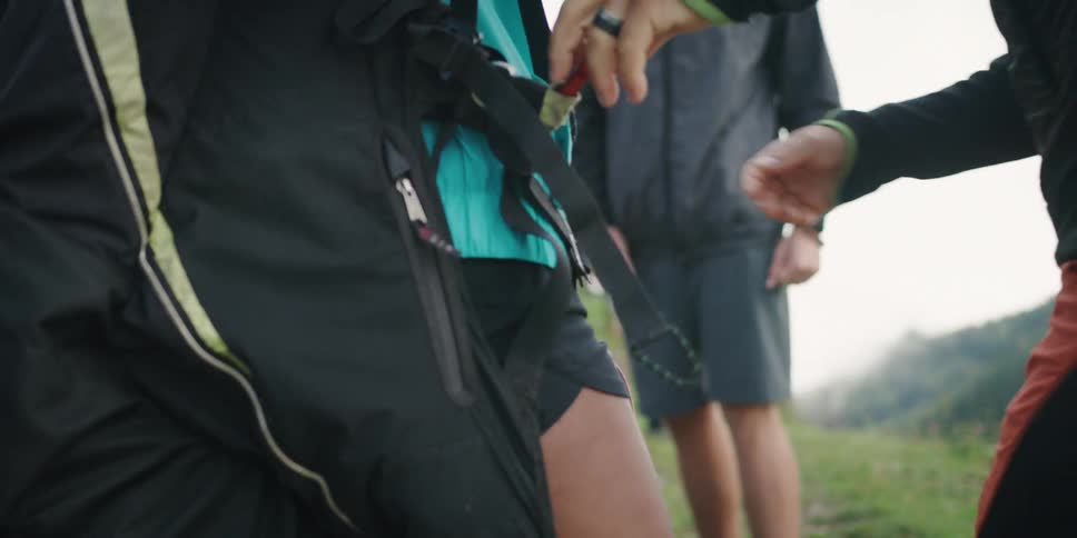 A man helping a young woman secure a the straps of a large backpack