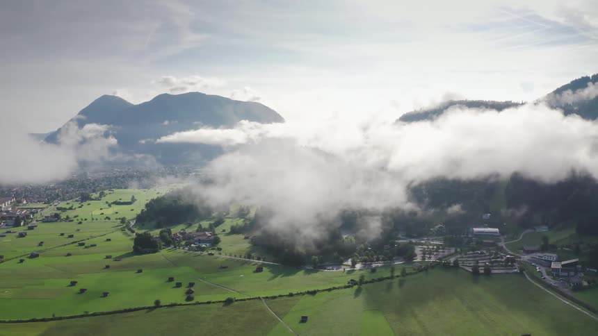 A small town with clouds above and mountains in the background