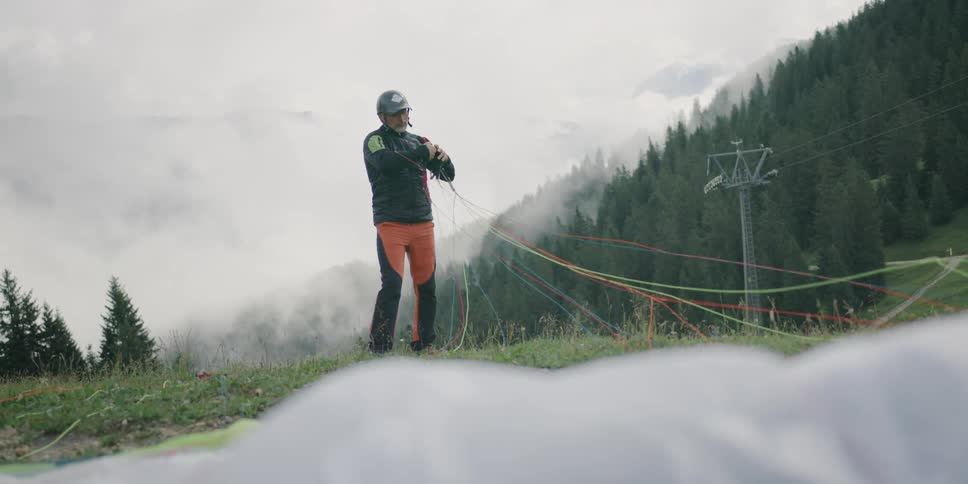 Man untanglin parachute lines for paragliding in the mountains