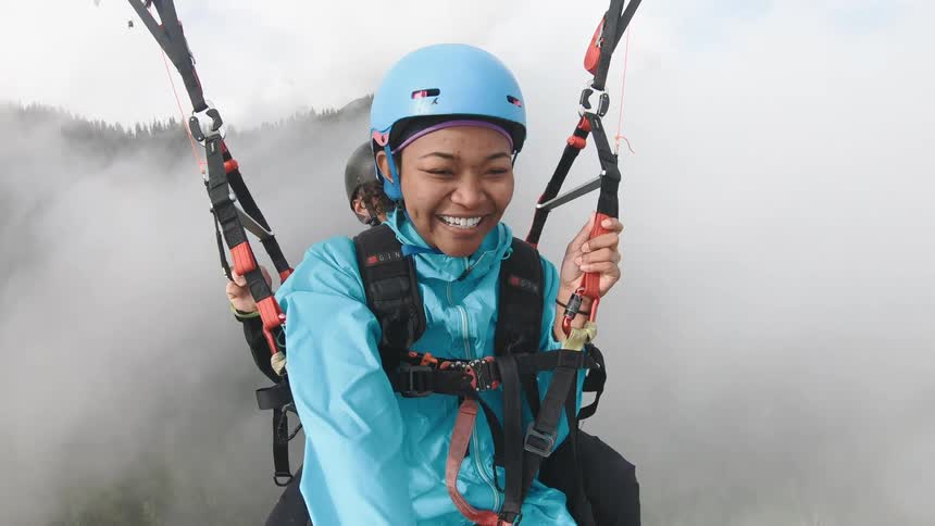 A man and a woman paragliding with trees in the background