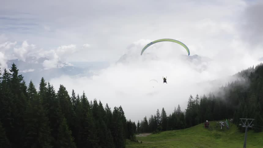 A person paragliding above hills and forest