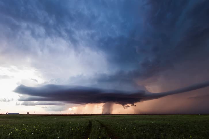 Large dark storm clouds form a tornado over a rural area