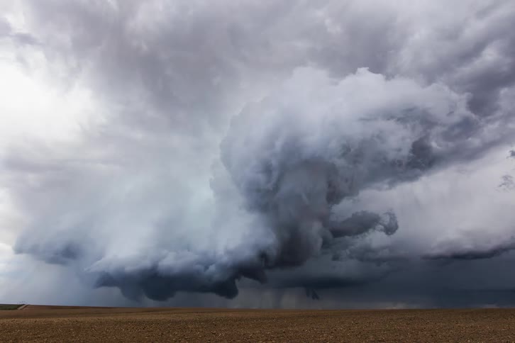 Dark clouds form funnels and rain bands across a flat landscape