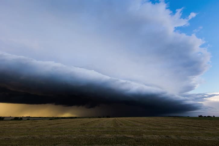 A grassy plain with the sky and clouds in the background