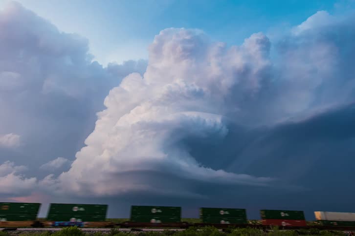 Large cloud bank moves overhead as train passes through plains