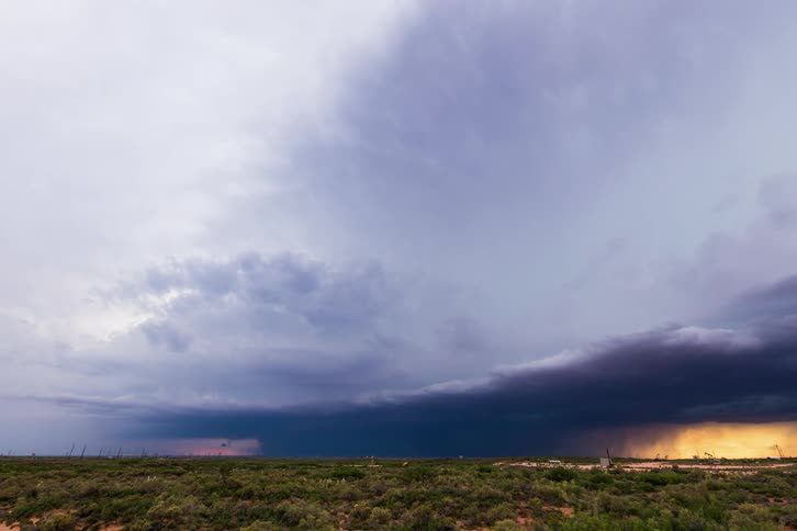 Timelapse of storm clouds releasing rain over plains at sunset