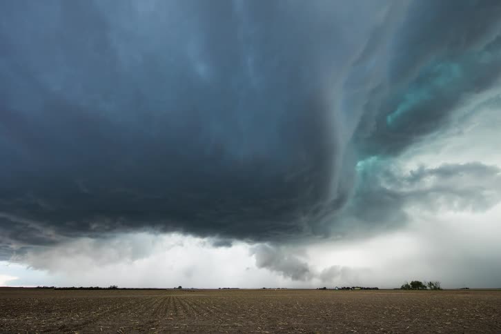 Lightning clouds swirling above an open field of grass