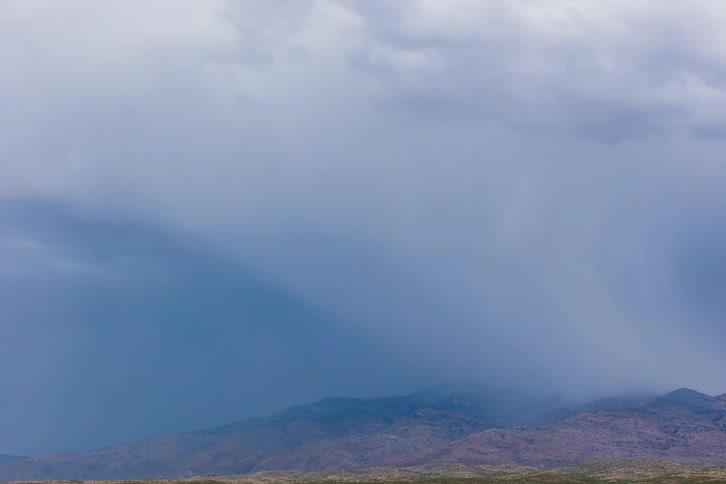 Timelapse of clouds releasing rain over mountains
