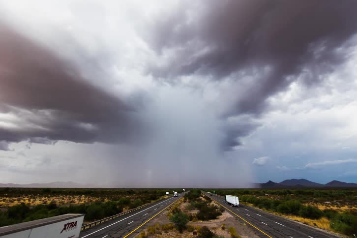 Timelapse of storm clouds releasing rain over highway on plains
