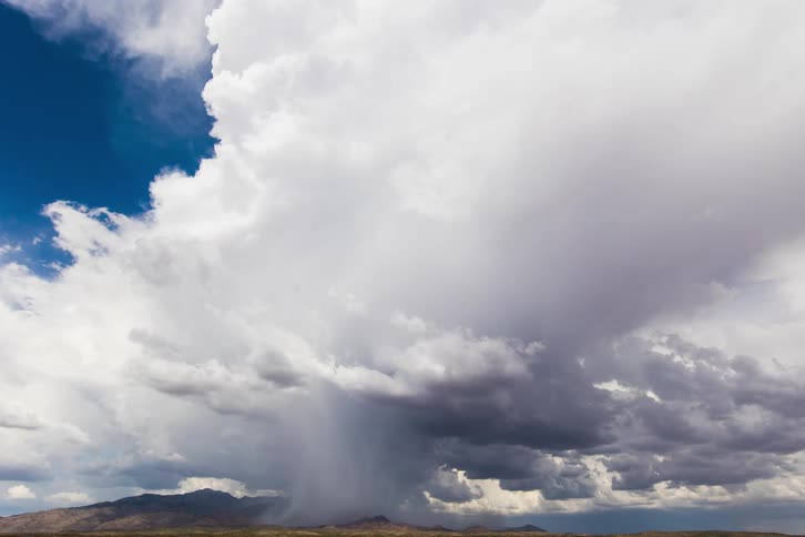 Clouds fill the sky and move above a mountain range