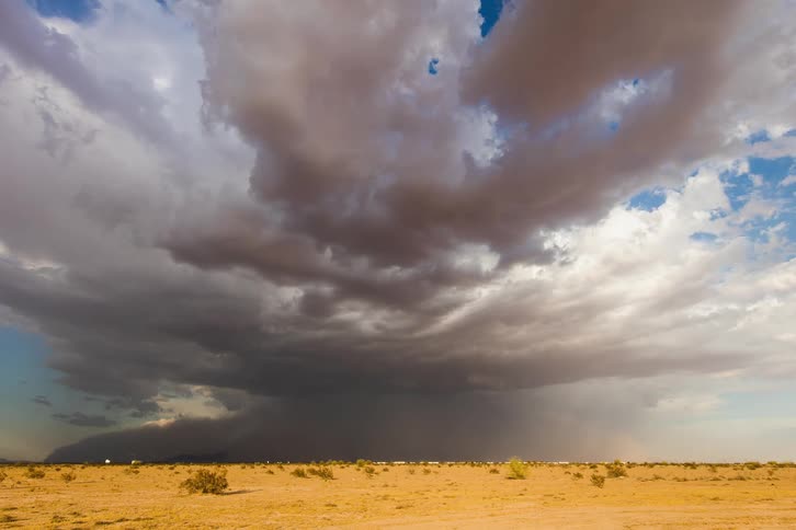 Timelapse of storm clouds releasing rain over dusty plains at day