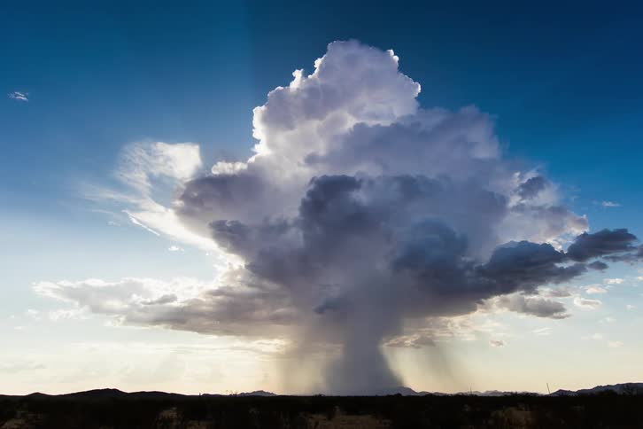 A grassy plain with a tornado cloud in the background