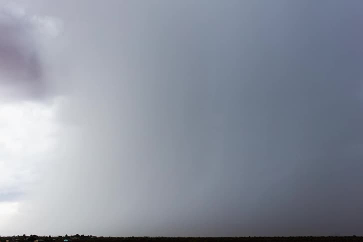 A grassy plain with the sky and clouds above