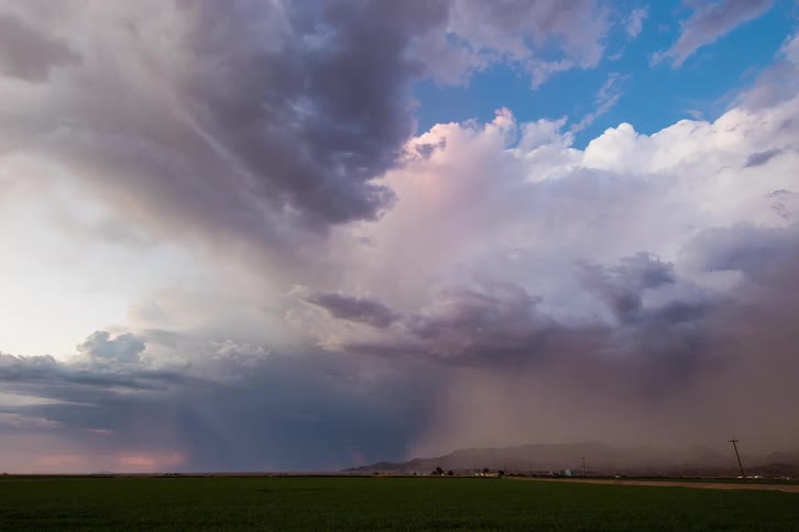 Lightning strikes and wind blows dirt over a rural highway