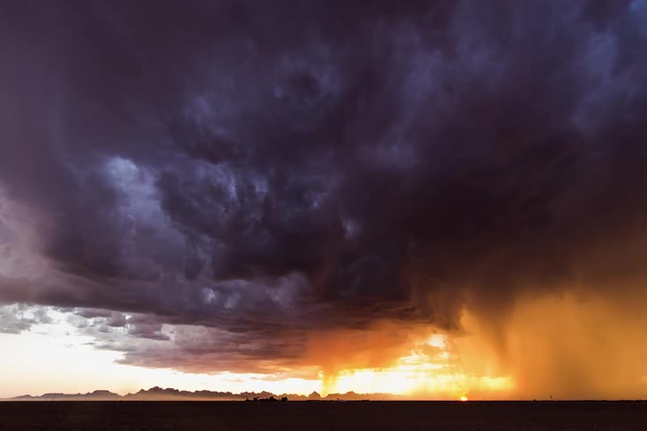 A grassy field with clouds and lightning above