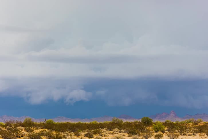 Time lapse of clouds rolling across a prairie with the mountains in the far off distance