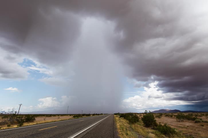 Vehicles travel a rural highway as a storm passes through