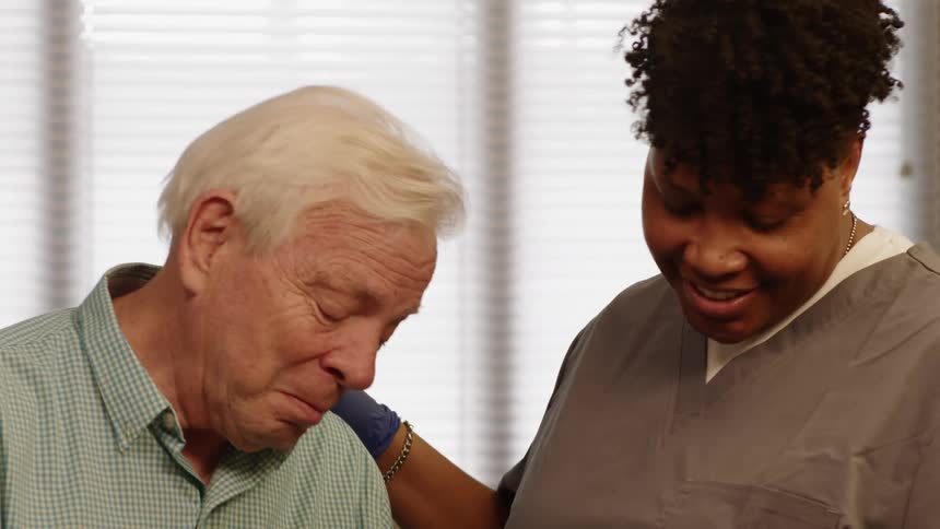Nurse talking and helping an elderly man