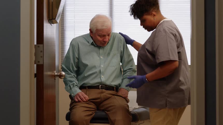 A nurse pulls up a patients pant leg to check his leg injury