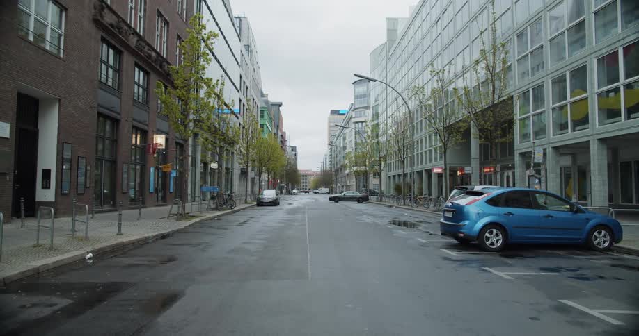 A city street lined with large buildings and parked vehicles in a city during the day