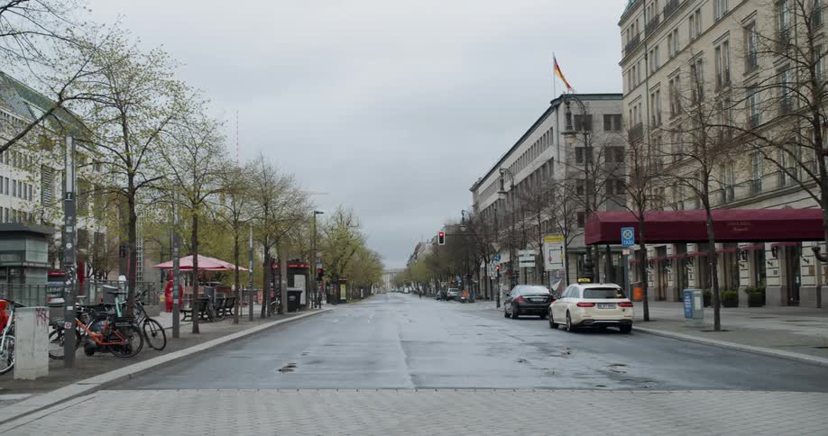 An empty city street with only a few cars parked on the side on a rainy gray day
