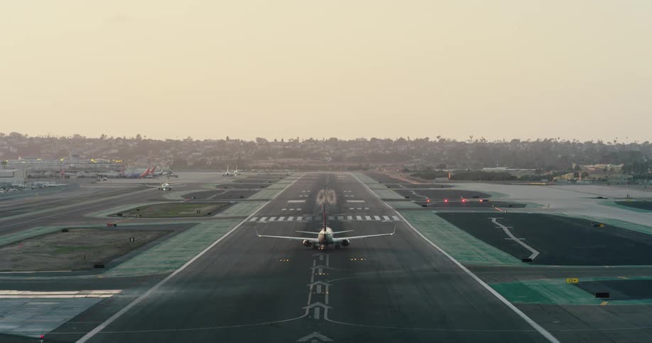 An airplane takes off from a runway while another plane turns onto the runway