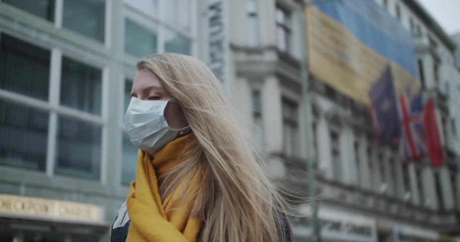 A teen wearing a mask stands outside a building