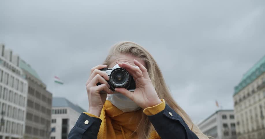 Woman takes photos with camera in city street at day