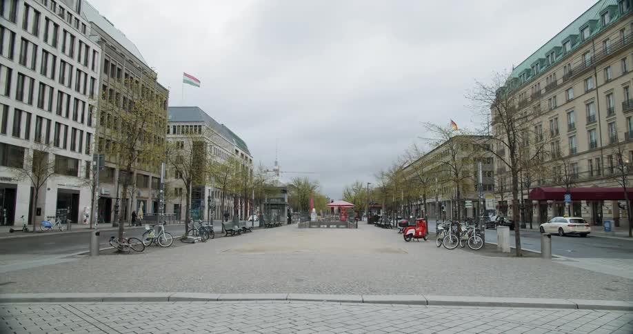 A bicyclist rides through an empty city with tall buildings lining both sides of the street