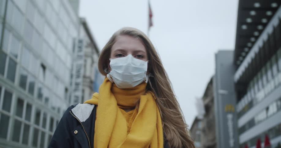 Female wearing a mask posing in middle of downtown during global pandemic