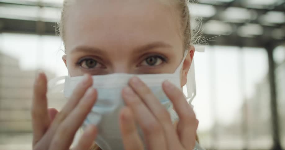 A woman adjusts her face mask