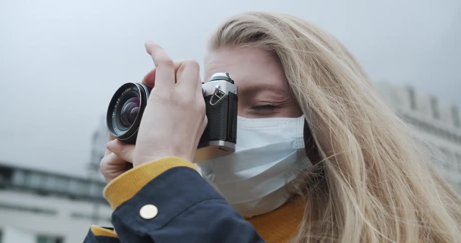 Woman wearing medical mask focuses camera